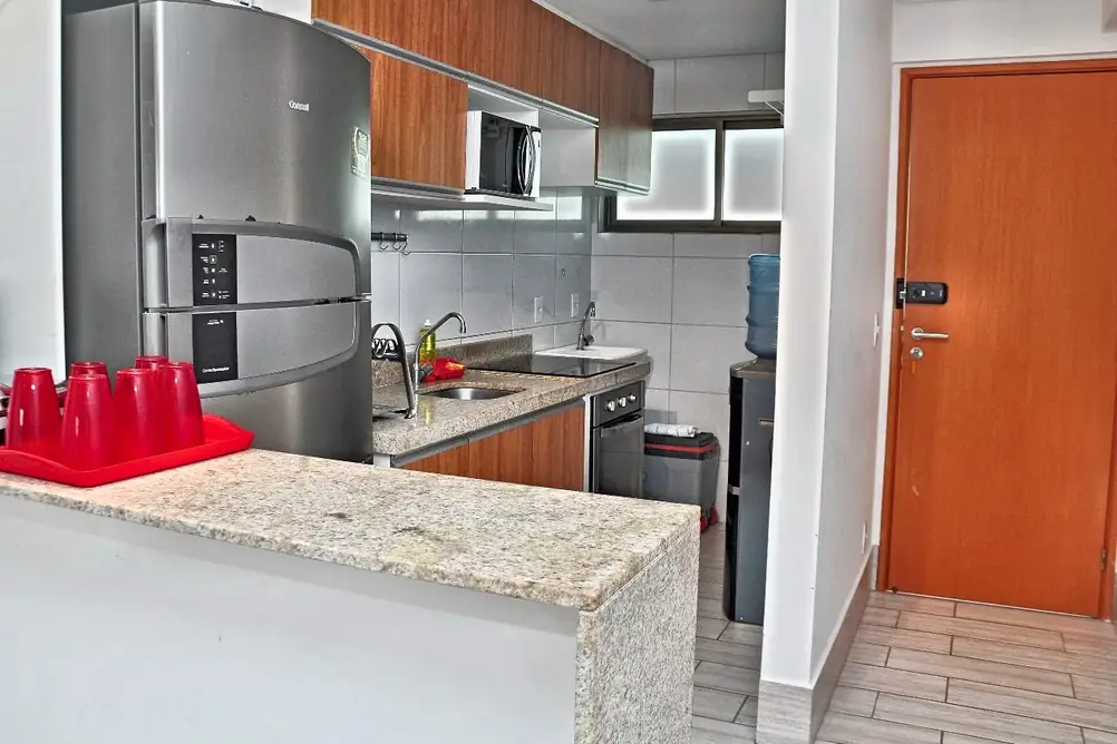Cozinha completa com geladeira, cooktop, micro-ondas e bancada de granito