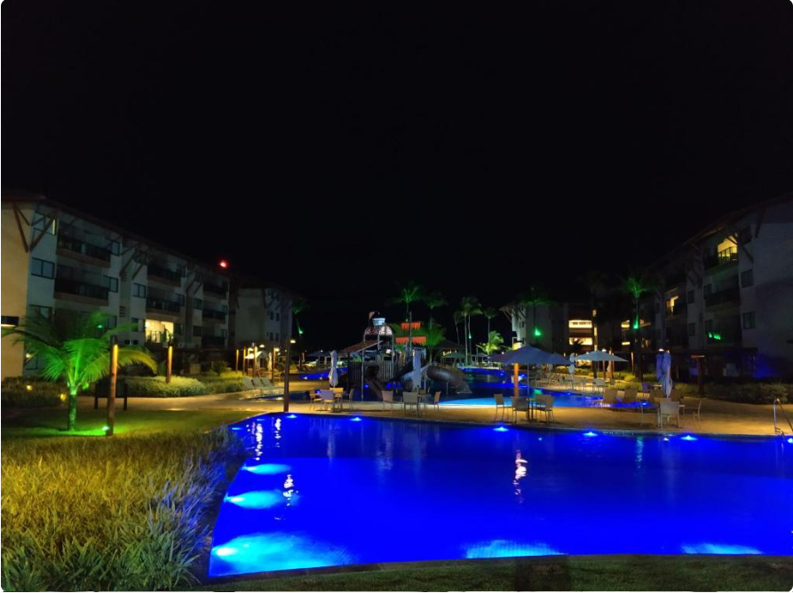 Área da piscina com iluminação noturna no Polinésia Resort