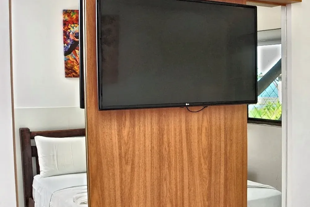 TV giratória entre a sala e o quarto, no painel de freijó